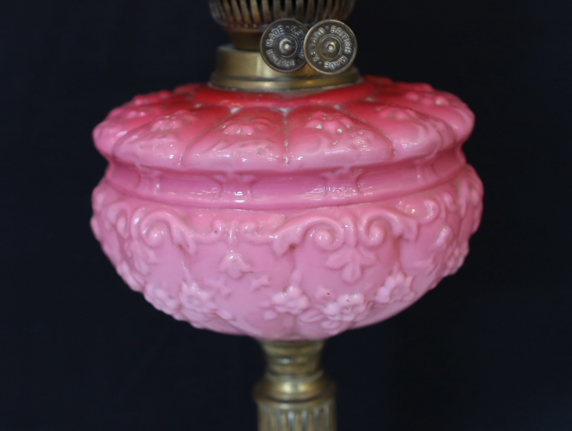 A late Victorian brass oil lamp with opaque pink glass reservoir, duplex mechanism, cranberry tinted etched glass shade and flue, height overall 65cm